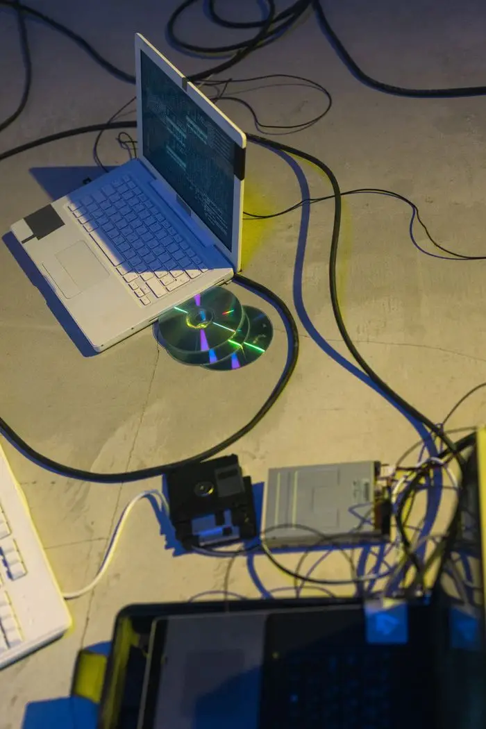 A modern and retro technology mix with laptops, floppy disks, and wires.